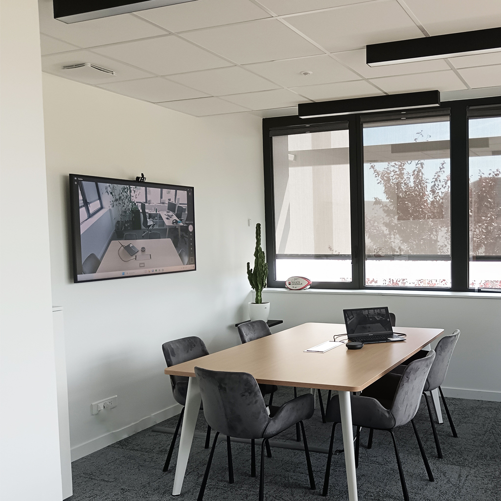 petite salle de visioconférence de 5 personnes avec un écran et camera au mur